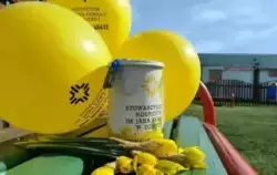 Żółte balony, kubek i kwiaty z akcji Pola Nadziei 2025