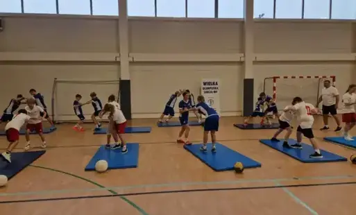 Uczniowie ćwiczący na matach w ramach Wielkiej Olimpijskiej Lekcji WF-u